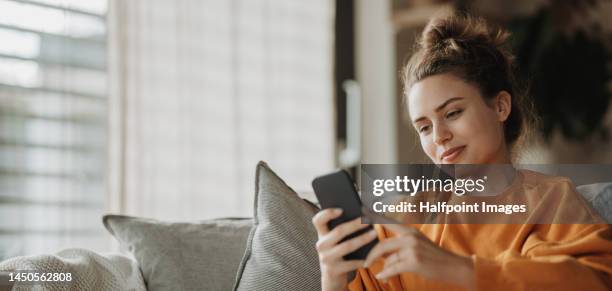 young woman resting on sofa with smartphone. - smartphone zuhause stock-fotos und bilder