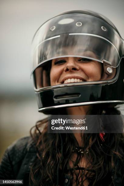happy woman with long hair wearing helmet - motorradfahrer stock-fotos und bilder