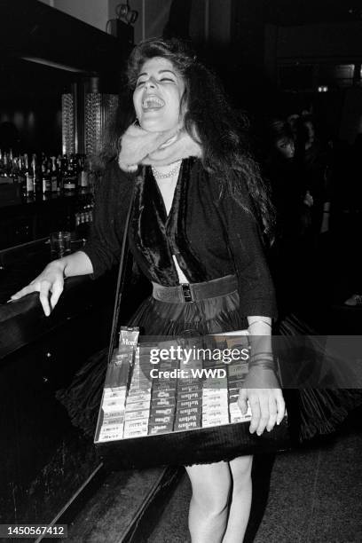 Young woman, dressed as a cigarette girl from the 1950s, holds a tray of cigarette packets at the club Heartbreaker, in New York City