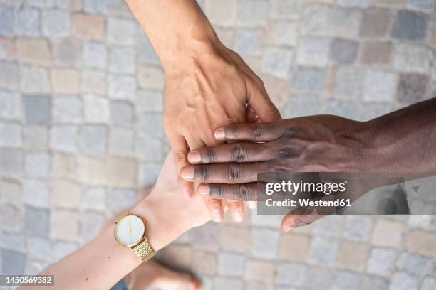 multiracial friends stacking hands over footpath - three hands stock pictures, royalty-free photos & images