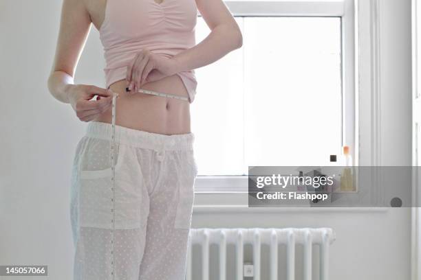 woman measuring her waist - vêtement de nuit photos et images de collection