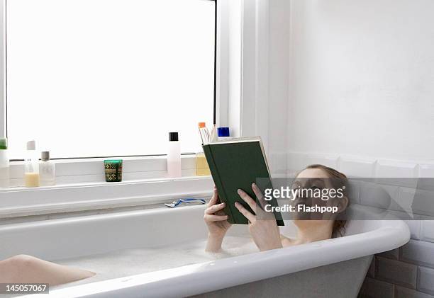 woman relaxing at home reading a book in the bath - frau badewanne stock-fotos und bilder