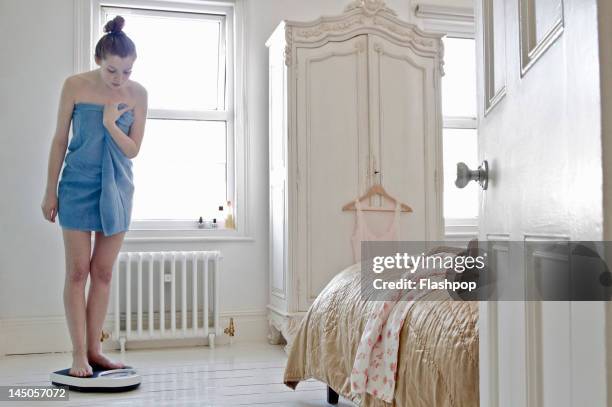 woman weighing herself at home - adelgazar fotografías e imágenes de stock