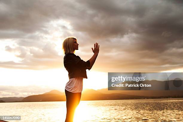 a beautiful young woman meditating as the sunsets over a lake in idaho. - pend orielle lake stock pictures, royalty-free photos & images