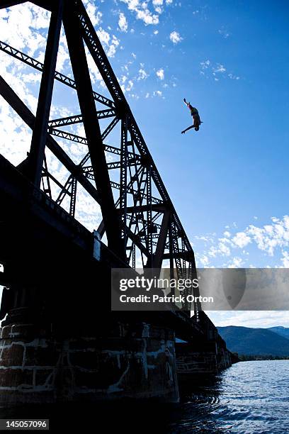 a athletic man flipping off a huge bridge on a sunny day in idaho. - pend orielle lake stock pictures, royalty-free photos & images