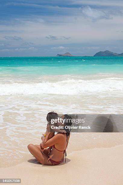 a mother giving her baby a kiss at the beach in waimanalo, hawaii. - kailua stockfoto's en -beelden