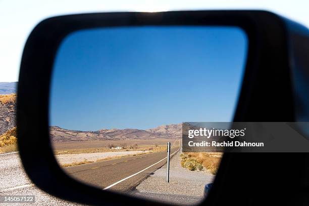 highway 50 in nevada, better known as the loneliest road in america, is reflected in a rearview mirror. - nevada road stock pictures, royalty-free photos & images