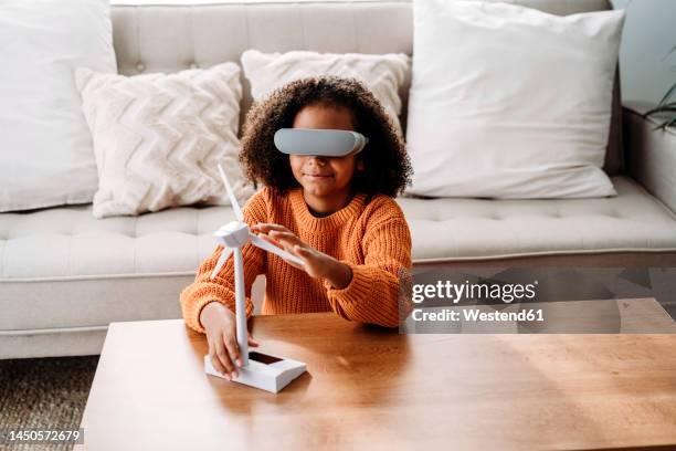 girl with virtual reality simulator sitting with wind turbine model in living room at home - vr headset kid stock pictures, royalty-free photos & images