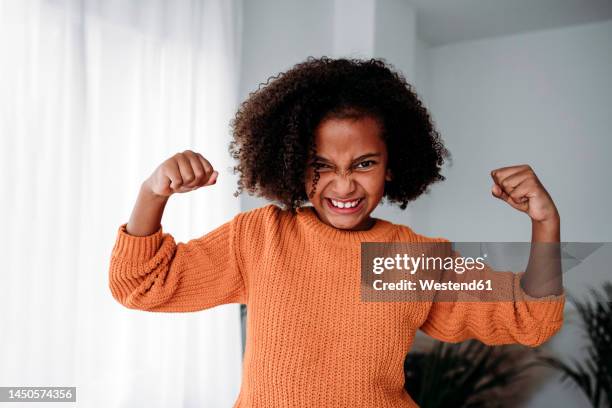 happy girl with curly hair flexing muscles at home - curly girl stock pictures, royalty-free photos & images