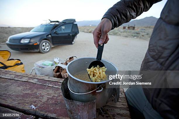 a man preparing a camp meal. - terrain stock pictures, royalty-free photos & images