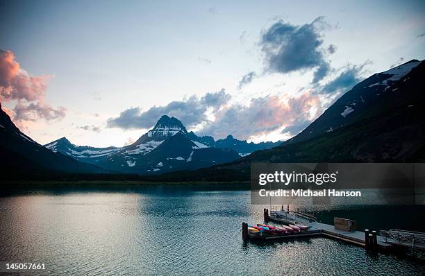 a lake with a dock and kayaks at dusk in a national park. - montana moody sky stock pictures, royalty-free photos & images