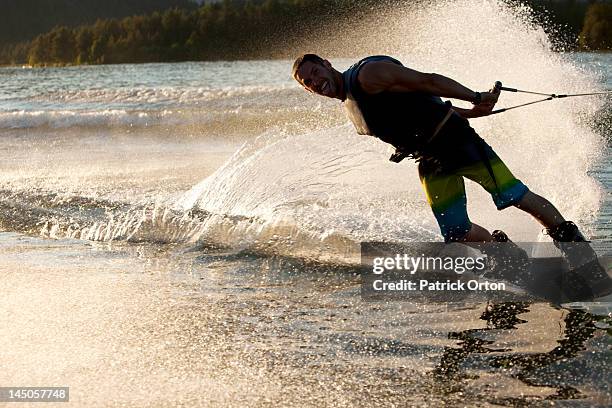 a professional wakeboarder smiles while he carves and slashes on lake pend oreille at sunset in sandpoint, idaho. - pend orielle lake stock pictures, royalty-free photos & images