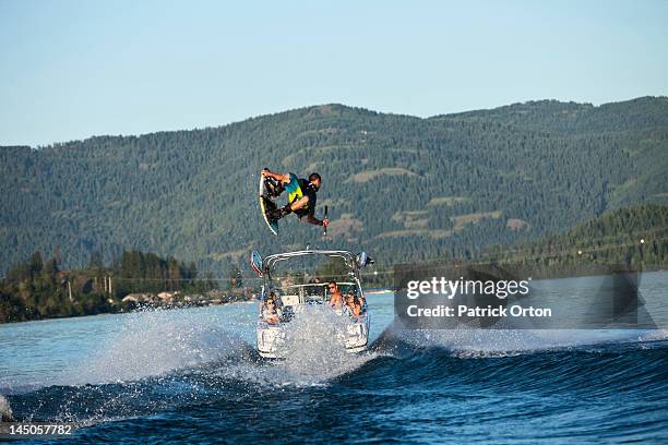 a professional wakeboarder jumps the wake on a lake in idaho. - sandpoint stock pictures, royalty-free photos & images