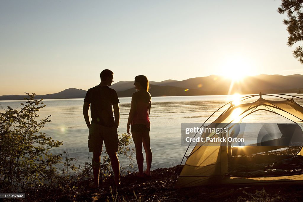 Two young adults laugh and smile at sunset on a camping and kayaking trip in Idaho.