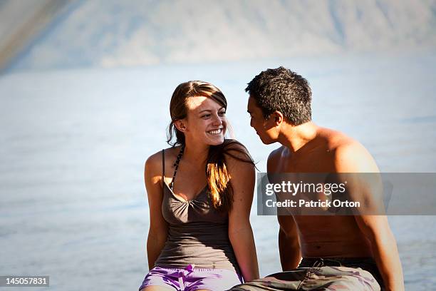 a happy young adult couple smile and laugh on a camping trip next to a lake in idaho. - pend orielle lake stock pictures, royalty-free photos & images