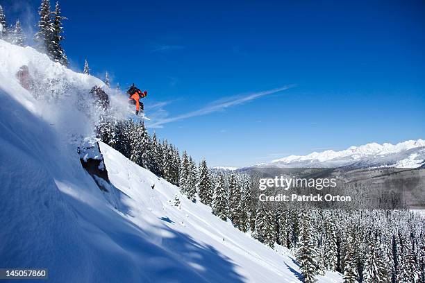 a athletic snowboarder jumping off a cliff on a sunny powder day in colorado. - snowy hill stock pictures, royalty-free photos & images