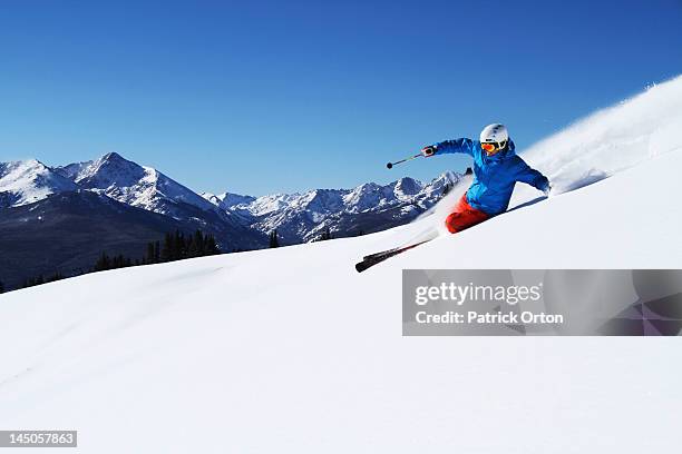 a athletic skier rips fresh powder turns on a sunny day in colorado. - vail colorado stock-fotos und bilder