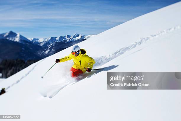 a athletic skier rips fresh powder turns on a sunny day in colorado. - vail colorado stock pictures, royalty-free photos & images