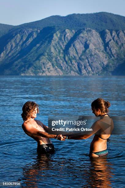 a young adult couple holding hands stand in a lake in idaho. - pend orielle lake stock pictures, royalty-free photos & images