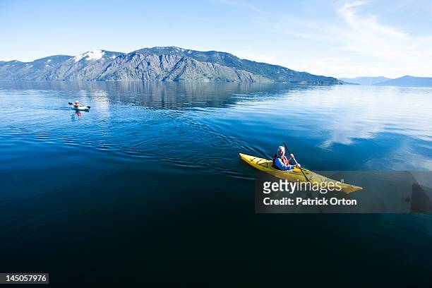 an happy adventurous retired couple kayaking on a huge calm lake in idaho. - sandpoint stock pictures, royalty-free photos & images