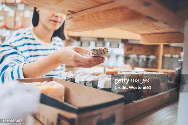 woman holding scented soap bar in zero waste store - magasin cosmétique photos et images de collection