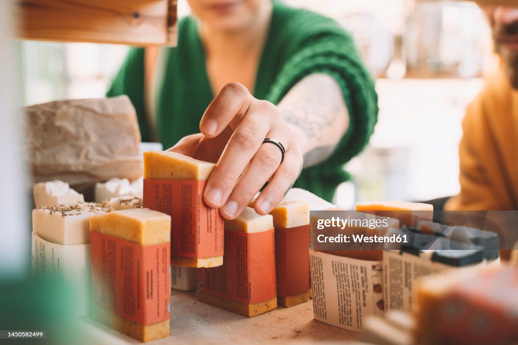 Woman picking up soap bar from rack in shop