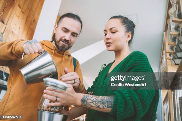 man helping woman to fill jar in retail store - iemand een plezier doen stockfoto's en -beelden