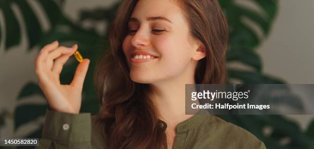 portrait of young woman with pill. - nutritional supplement imagens e fotografias de stock
