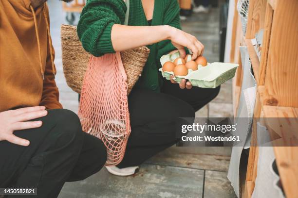 woman examining eggs in carton by man at shop - äggkartong bildbanksfoton och bilder