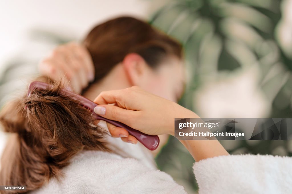 Rear view of young woman combing her hair.