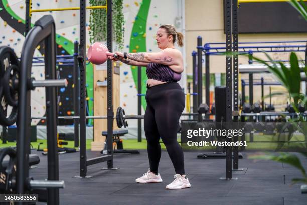 young overweight woman working out with kettlebell in gym - kettle bell stock pictures, royalty-free photos & images