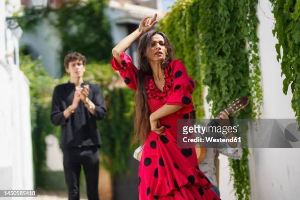 flamenco dancer performing with guitarist near wall - flamencos fotografías e imágenes de stock