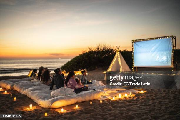 group of people watching a movie at the outdoors cinema - beach night stockfoto's en -beelden