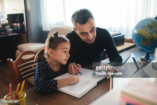 padre ayudando a su hija con su tarea - educación en el hogar fotografías e imágenes de stock