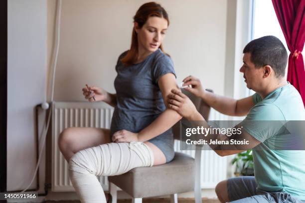 ein mann reinigt eine stelle am arm einer schwangeren frau, bevor er ihr medikamente injiziert. - gesundheitsvorsorge stock-fotos und bilder