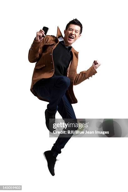 stylish young man with moblie phone - jumping casual clothing studio shot stock pictures, royalty-free photos & images