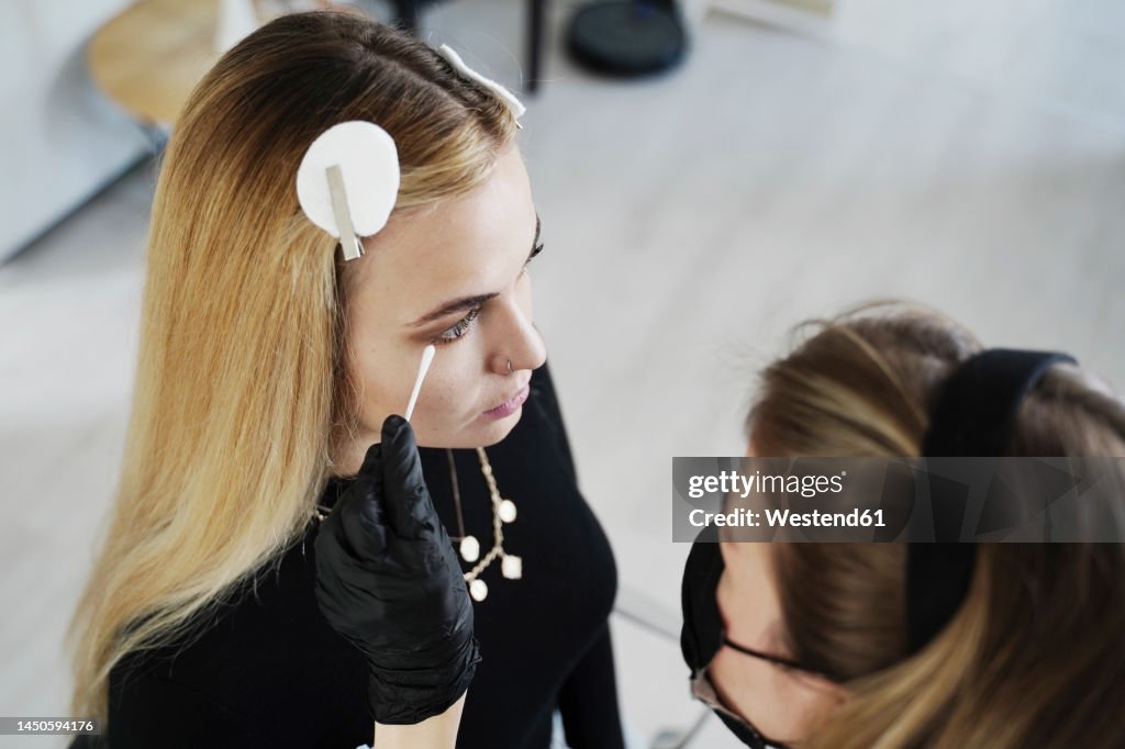 Beautician applying make-up with cotton swab in salon