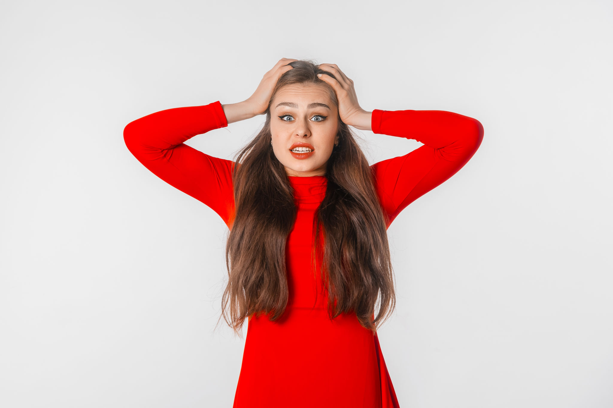 Portrait of the shocked anxious young woman in panic, holding hands on head and worrying, standing frustrated and scared against white studio background. Psychology, depression, bad mood, stress Portrait of the shocked anxious young woman in panic, holding hands on head and worrying, standing frustrated and scared against white studio background. Psychology, depression, bad mood, stress