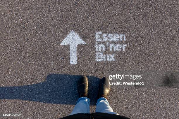 woman standing by text and arrow symbol on street - low section of woman standing in front of arrow sign on road stock pictures, royalty-free photos & images