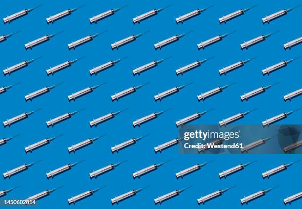 pattern of rows of syringes flat laid against blue background - flat lay background stock illustrations