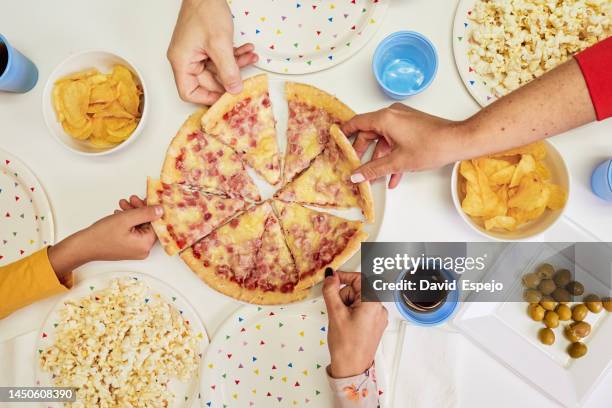 family taking pizza slices while having a dinner party together. - four people foto e immagini stock
