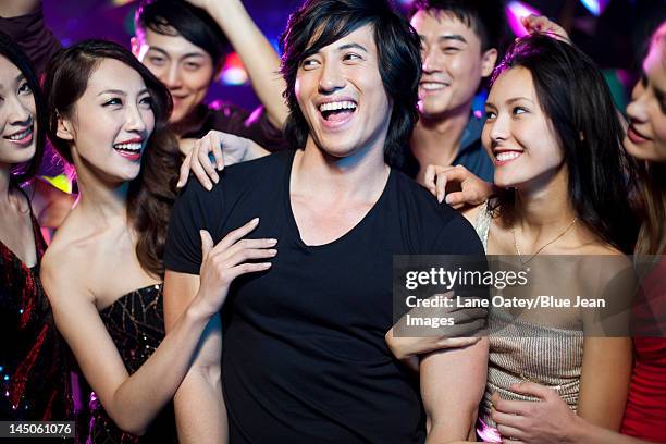 young man surrounding by beautiful women in nightclub - surrounding ストックフォトと画像