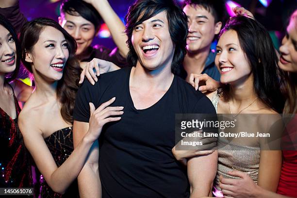 young man surrounding by beautiful women in nightclub - surrounding stock pictures, royalty-free photos & images