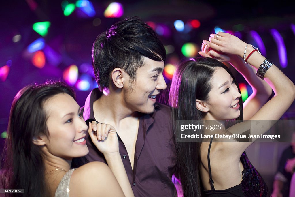 Young man surrounding by beautiful women in nightclub