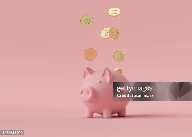 gold coins falling into pink piggy bank - savings fotografías e imágenes de stock