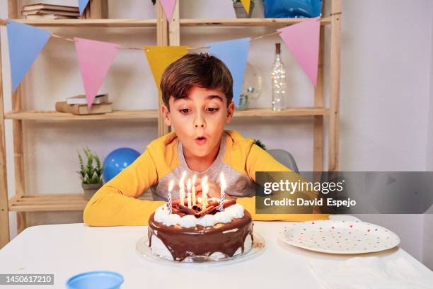 young boy blowing the candles on the birthday cake while celebrating with a party at home. - geburtstag 11 stock-fotos und bilder