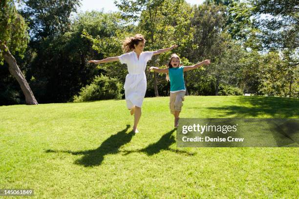 Mother And Daughter Running Down Hill In Park, Foto de stock