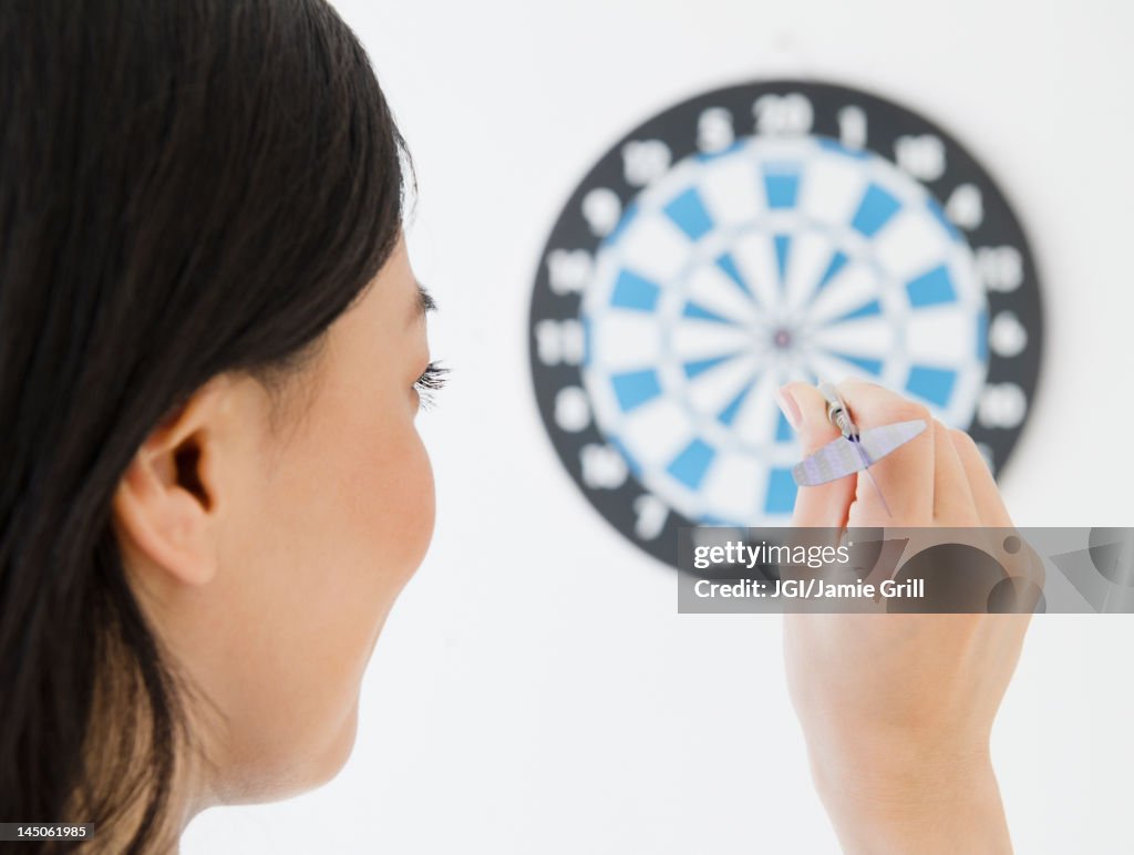 Japanese woman throwing dart at dartboard