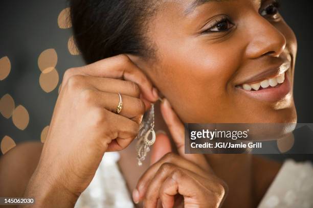black woman putting on earring - ohrring stock-fotos und bilder