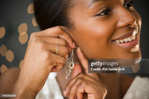 black woman putting on earring - ear piercing stock pictures, royalty-free photos & images